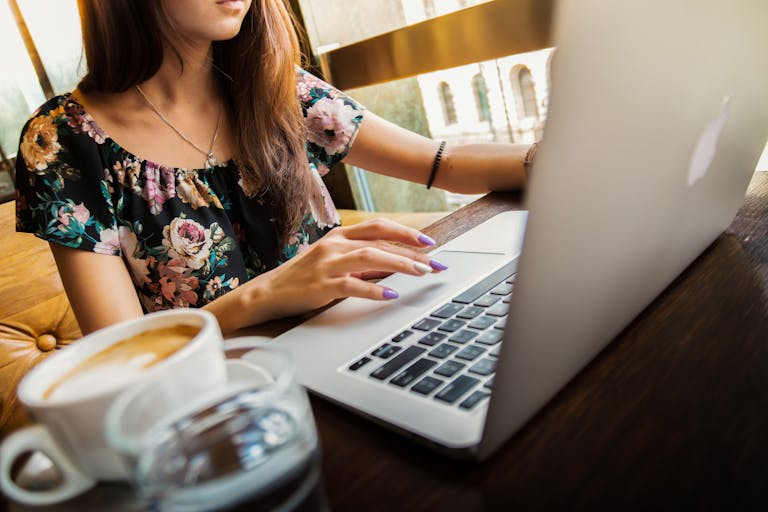 A woman working on a laptop in a cafe, sipping coffee, embodying a modern remote work lifestyle.